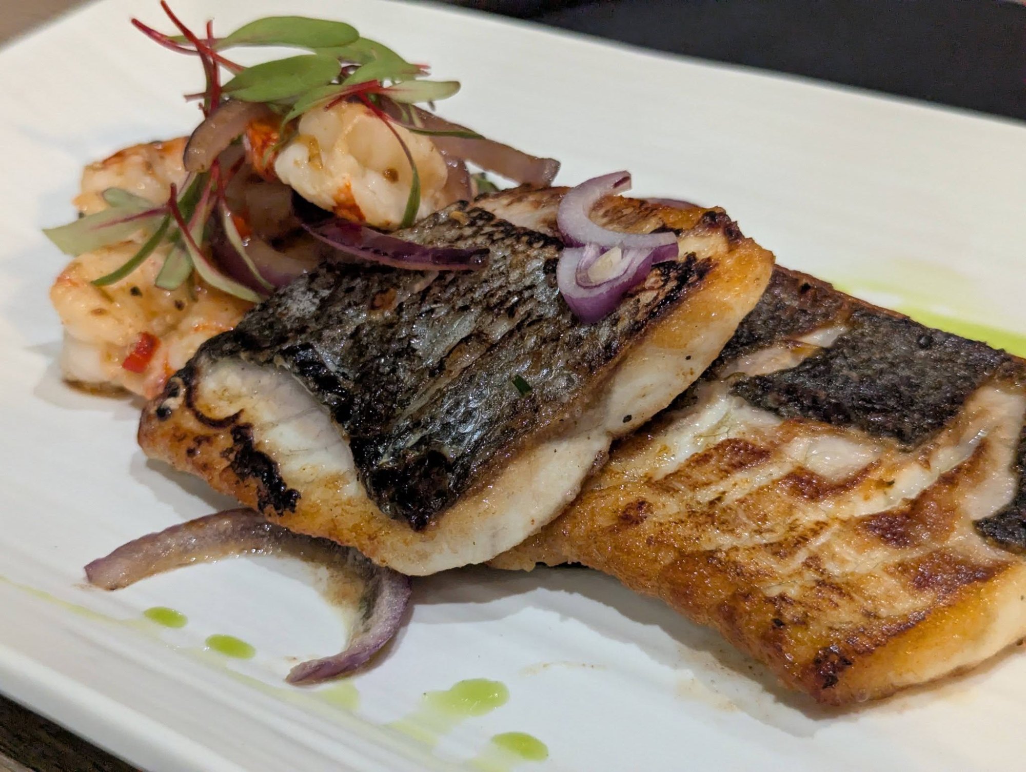 Grilled sea bass fillet with prawns and herb oil